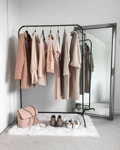 an iron rack with clothes and shoes on it in front of a mirrored wall mounted coat rack