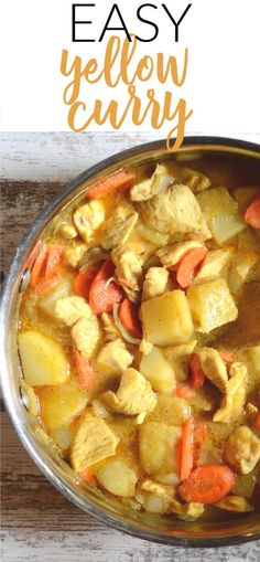 a bowl filled with chicken curry and carrots on top of a wooden table next to a