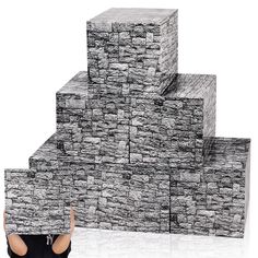 a woman is holding up a large stack of stone blocks in front of her face