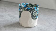 a white and blue flowered vase sitting on top of a gray table next to a wall