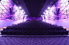 an empty auditorium with rows of seats and purple lighting