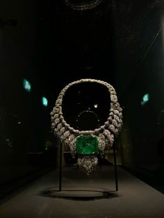 an emerald and diamond necklace on display in a dark room