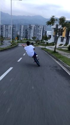 a man riding a skateboard down the middle of a street next to tall buildings