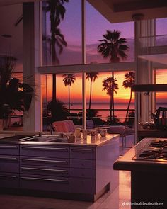 the kitchen is very large and has an island in front of it, while the sun sets over the ocean