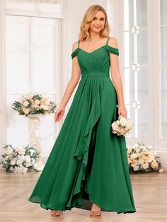 a woman in a green dress standing on a wooden floor with flowers and greenery