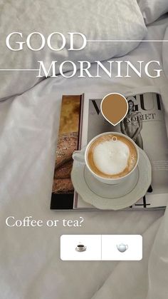 a cup of coffee sitting on top of a bed next to a book and magazine