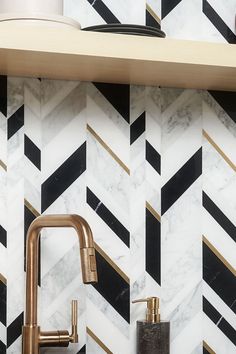 a kitchen with marble counter tops and gold faucets on the wall above it