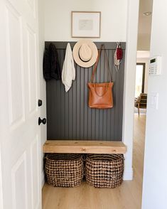 the entryway is decorated with baskets, hats and coats hanging on the gray wall