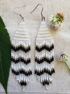 two white and black beaded earrings next to a flower