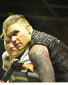 a man with tattoos on his arm holding a microphone