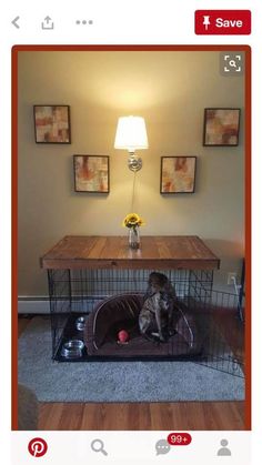 a dog sitting in its cage on the floor next to a table with a lamp