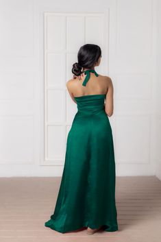 the back of a woman in a green dress looking at an open door with white walls