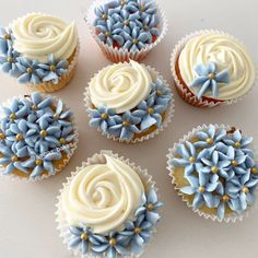 six cupcakes decorated with blue and white frosting, arranged on a table