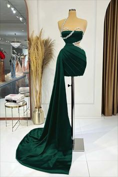 a dress on display in front of a mannequin wearing a green evening gown