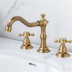 two golden faucets on a white sink in a bathroom