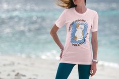 a woman standing on the beach with her hair blowing in the wind wearing a pink shirt