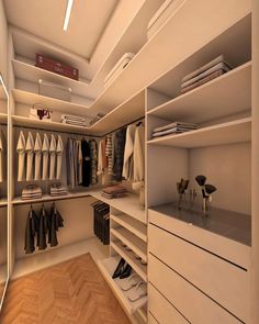 a walk in closet filled with lots of white shelves and clothes on top of wooden flooring