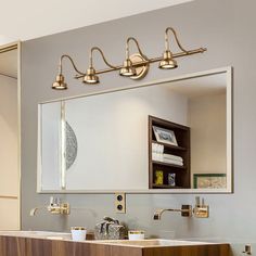 a bathroom with a sink, mirror and lights on the wall above it's counter