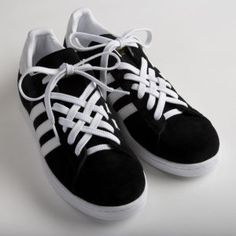 a pair of black and white sneakers with laces on the top, sitting on a white surface