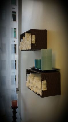 two brown shelves with towels and candles on them