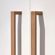 two pieces of wood sitting on top of a white wall next to eachother