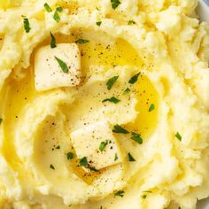 mashed potatoes with butter and parsley in a white bowl on a gray surface