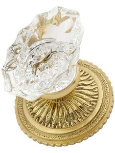 a glass candle holder sitting on top of a gold plate