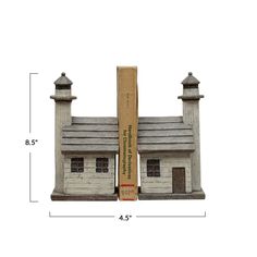 a book is sitting on top of a small house with two chimneys and a roof