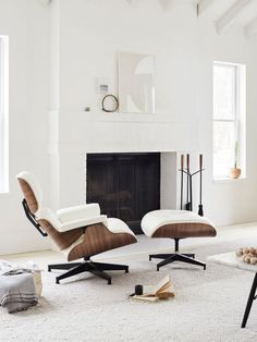 an eames chair and ottoman in front of a fireplace