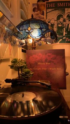 a record player sitting on top of a turntable next to a lamp and poster