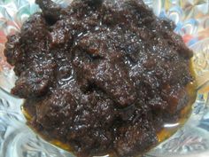 a bowl filled with brown stuff on top of a glass table covered in plastic wrappers