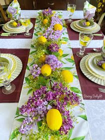 the table is set with yellow and purple flowers, lemons, and other greenery