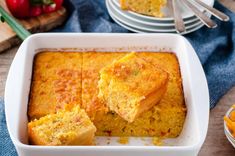 cornbread casserole in a white dish on a wooden table with other dishes and utensils