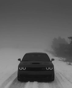 a car driving down a snow covered road in the middle of the day with headlights on