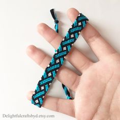 a hand holding a blue and black bracelet