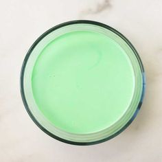 a glass filled with green liquid sitting on top of a table