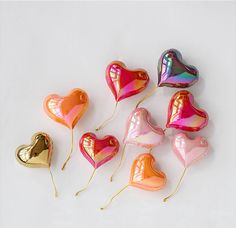 heart shaped candy lollipops are arranged on a white surface with gold foil