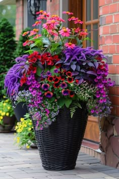 a large basket filled with lots of flowers sitting on top of a sidewalk next to a brick building