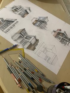 pencils and crayons are sitting on a table next to some house drawings