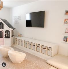 a living room with white furniture and a flat screen tv mounted above the entertainment center