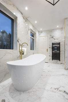 a large white bathtub sitting in the middle of a bathroom next to a window