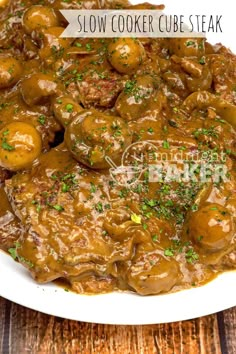 a white plate topped with meat covered in gravy and garnished with parsley