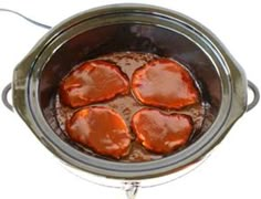 four pieces of cooked meat in a slow cooker with sauce on the top and bottom