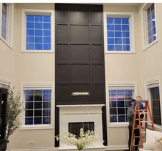 a living room filled with furniture and a fire place in front of a windowed wall