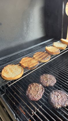 hamburgers and burger patties cooking on an outdoor grill