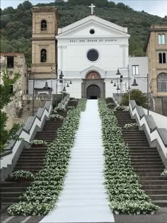 a church with stairs leading up to it and flowers growing all over the walkways