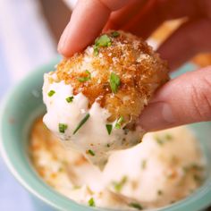 a person dipping something into a small bowl with some kind of sauce on it and garnished with parsley