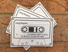 three stickers with the words song request and an audio cassette on them sitting against a brick wall