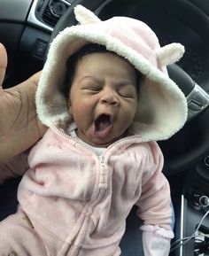 a baby is wearing a pink outfit and has it's mouth open while sitting in the driver's seat