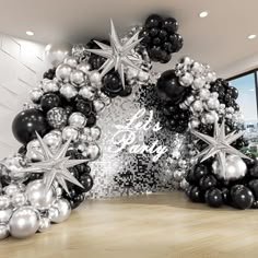 an arch made out of black and silver balloons with stars on them in front of a large window